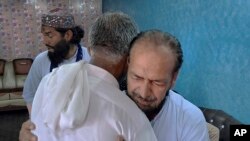 People offer their support to Raja Yousaf, right, whose son Raja Sajid is missing after a shipwreck off the Greek coast, in Bindian village in Kotli, a district of Pakistan's administrator Kashmir, June 18, 2023. 