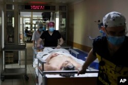 Medical workers transport a Ukrainian serviceman on the stretcher before a surgery operation at the military hospital in Kyiv, Ukraine, on Thursday, May 5, 2023. (AP Photo/Alex Babenko)