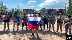 Yevgeny Prigozhin (depan), kepala perusahaan militer swasta grup "Wagner" berbicara sambil memegang bendera Rusia di depan tentaranya di Bakhmut, Ukraina.