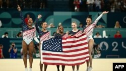នាង Simone Biles (កណ្តាល) និងមិត្តរួមក្រុមរបស់នាងអបអរបន្ទាប់ពីក្រុមសហរដ្ឋអាមេរិក បានឈ្នះការប្រកួតវគ្គផ្តាច់ព្រ័ត្រនៃកីឡាកាយ​សម្ព័ន្ធ​​នារីក្នុងអំឡុងការប្រកួតកីឡាអូឡាំពិកទីក្រុងប៉ារីសឆ្នាំ ២០២៤។