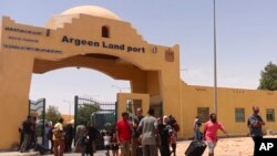Evacuees carry their luggage as they cross into Egypt through the Argeen land port, after being evacuated from Sudan, April 27, 2023.
