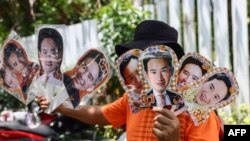 A vendor holds up signs with the face of Move Forward Party leader and prime ministerial candidate Pita Limjaroenra before the partys final campaign event in Bangkok on May 12, 2023, ahead of Thailand's May 14 general election.