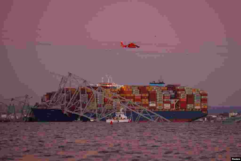 A helicopter flies over the scene of the Francis Scott Key Bridge collapse in Baltimore, March 26, 2024.&nbsp;