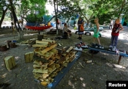 Local residents charge their phones using a portable generator after floodwaters receded following the collapse of the Kakhovka dam, in the town of Hola Prystan in the Kherson region, Russian-controlled Ukraine, June 17, 2023.