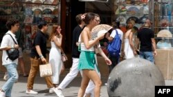 FILE - A woman fans herself to cool off in the midst of a heat wave in Madrid on Aug. 9, 2023. 