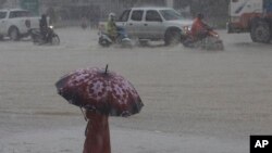 រូបឯកសារ៖ ក្មេងស្រីម្នាក់បាំងឆ័ត្រ ក្នុងពេលភ្លៀងធ្លាក់ដ៏ធំមយយ នៅជាយរាជធានីភ្នំពេញ កាលពីថ្ងៃទី ១១ ខែតុលា ឆ្នាំ ២០២០។ 