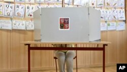 A woman prepares her ballots for the European Parliament elections at a polling station in Prague, Czech Republic, June 7, 2024.