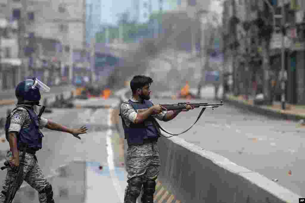 A policeman aims his weapon at protesters during a curfew imposed following violence during protests against Prime Minister Sheikh Hasina and her government, in Dhaka, Aug. 5, 2024.