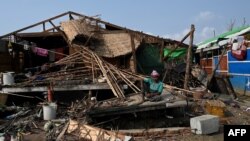 FILE - A Rohingya woman sits by her destroyed house at Ohn Taw Chay refugee camp in Sittwe on May 16, 2023, in the aftermath of Cyclone Mocha's landfall. 