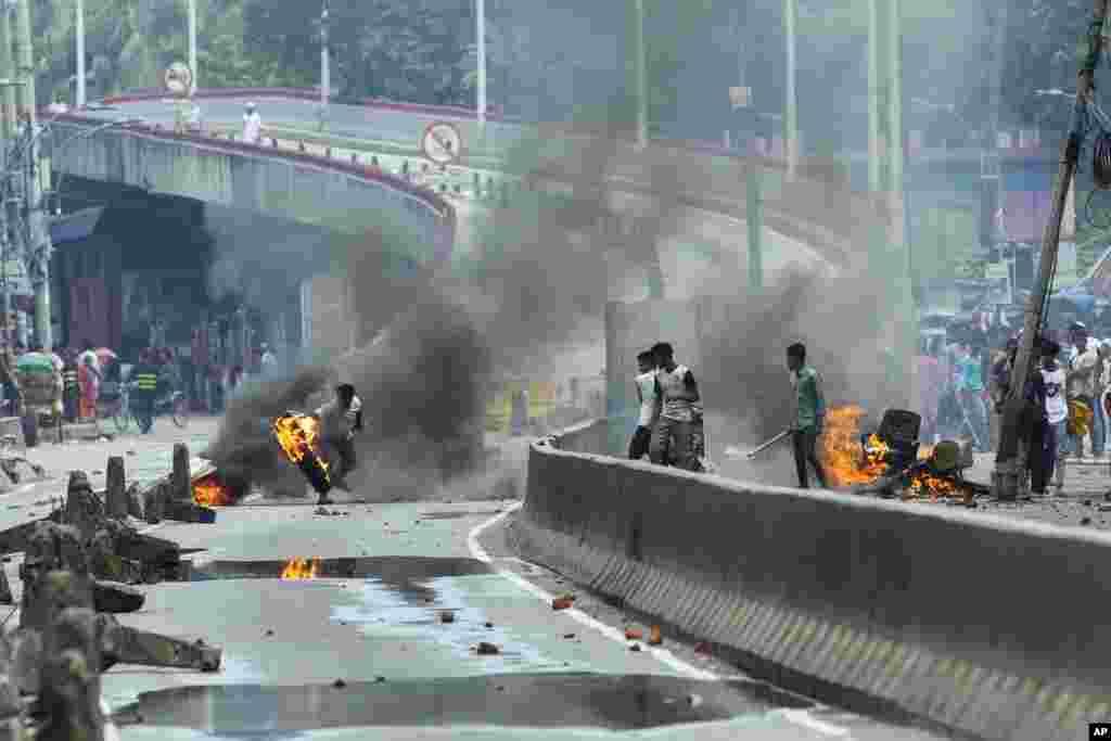A protester throws a rubber tire on fire during a protest against Prime Minister Sheikh Hasina and her government, in Dhaka, Aug. 5, 2024.
