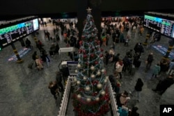 Travelers look at the information boards as they wait for their trains at Euston station in London, Dec. 22, 2023.