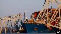 Cranes stand by as the wreckage of the Francis Scott Key Bridge rests on the container ship Dali in Baltimore, Maryland, March 30, 2024, in Baltimore.