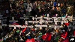FILE - Flowers are piled around crosses with the names of the victims killed in a school shooting as people visit a memorial at Robb Elementary School to pay their respects, in Uvalde, Texas, May 31, 2022. 