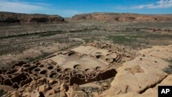 FILE - A hiker sits on a ledge above Pueblo Bonito, the largest archeological site at the Chaco Culture National Historical Park, in northwestern New Mexico, Aug. 28, 2021. 
