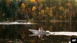 Law enforcement officers search the Androscoggin River on Friday for Robert Card, an Army reservist accused of shooting people at a bowling alley and bar in Maine. Later the same day, Card was found dead.