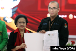 Ketua umum PDIP Megawati Soekarnoputri menyerahkan dokumen persyaratan calon presiden Ganjar Pranowo dan calon wakil presiden Mahfud MD kepada Ketua KPU Hasyim Asyari ada Kamis (19/10) di Jakarta. (VOA/Indra Yoga)