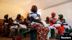 FILE - Mothers hold their children as they wait to get them vaccinated at in Datcheka, Cameroon, Jan. 22, 2024. 