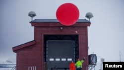 French AWIPEV logistics engineers Tommy Jegoue (right) and Apolline Pibarot release a weather balloon into the stratosphere to measure weather parameters in Ny-Aalesund, April 6, 2023.