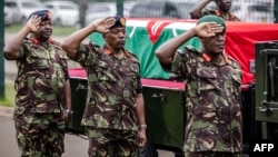 Des membres de l'armée kenyane font le salut militaire à côté du cercueil transportant le corps du chef des forces de défense kenyanes, le général Francis Omondi Ogolla, au complexe sportif d'Ulinzi à Nairobi, le 20 avril 2024. (Photo par LUIS TATO / AFP)