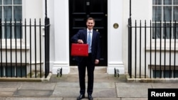 Menteri Keuangan Inggris Jeremy Hunt memegang kotak anggaran di Downing Street, London, Inggris, 15 Maret 2023. (REUTERS/Peter Nicholls)