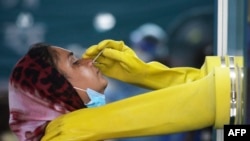 Karyawan Aan dari Mugda Medical College and Hospital mengumpulkan sampel swab dari seorang warga untuk menguji virus corona COVID-19, di Dhaka, Bangladesh. (Foto: AFP)