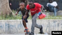 People take cover from gunfire near the National Palace, in Port-au-Prince, Haiti, March 21, 2024.