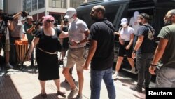 Yacht crew members, who allegedly caused a forest fire on the island of Hydra after launching fireworks from the vessel, are transferred to the prosecutor's office in Piraeus, Greece, June 23, 2024. (Giannis Panagopoulos/Eurokinissi via Reuters)