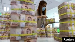 រូបឯកសារ៖ បុគ្គលិកធនាគារ​ម្នាក់​កំពុង​ត្រួតពិនិត្យ​ក្រដាសប្រាក់​ថៃ​ នៅ​ក្នុងធនាគារ Kasikornbank ក្នុងទីក្រុងបាងកក ប្រទេសថៃ កាលពីថ្ងៃទី២៦ ខែមករា ឆ្នាំ២០២៣។ 