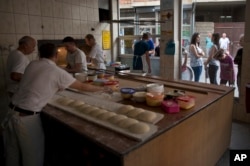 Para pembuat roti menyiapkan adonan dengan bahan-bahan yang dibawa oleh keluarga yang menunggu di luar, untuk menyiapkan dan memanggang pitalka di kota Prizren, Kosovo selatan, Jumat, 17 Juni 2016. (AP/Visar Kryeziu)