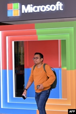 Seorang pria berjalan di samping logo Microsoft saat acara Microsoft Build AI Day di Jakarta, 30 April 2024. (Adek BERRY / AFP)
