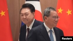 South Korean President Yoon Suk Yeol and Chinese Premier Li Qiang move their positions during a meeting at the Presidential Office in Seoul, South Korea, May 26, 2024.