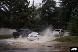Vehicles drive down a flooded roadway due to severe rain in Los Angeles, California, on Feb. 25, 2023.