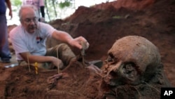 FILE - Rogelio Goiburú, a member of Paraguay's Truth and Justice Commission, looks at skeletal remains found buried at the National Police Special Forces headquarters in Asuncion, Paraguay, March 19, 2013.