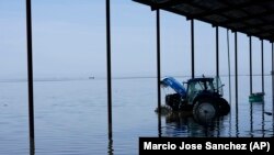 A tractor sits in flood water on the Hansen Ranches property after a series of storms Tuesday, April 25, 2023, in Corcoran, Calif. (AP Photo/Marcio Jose Sanchez)