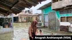 Seorang pelajar sedang melintasi kawasan banjir rob di Kecamatan Medan Belawan, Kota Medan, Sumatra Utara, Jumat 19 Mei 2023. (VOA/Anugrah Andriansyah)