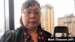 Rena Sapp, outside a courtroom on Oct. 21, 2019, in Anchorage, Alaska, shows a photo of her sister, Veronica Abouchuk, who was tortured and murdered by Brian Steven Smith.