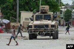 A child walks by a police vehicle in Port-au-Prince, Haiti, on April 26, 2024.