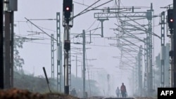 People walk through railway tracks amid smoggy conditions on the outskirts of New Delhi, India, Oct. 30, 2023.