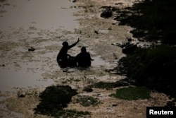Seorang nelayan melempar ikan yang ditangkap dari sungai Brantas ke darat di Mojokerto, Provinsi Jawa Timur, 30 Juli 2019. (REUTERS/Willy Kurniawan)