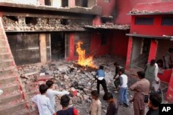Ljudi i deca gledaju crkvu oštećenu i spaljenu u napadu besne rulje u Džaranvalu, Pakistan, 16. avgusta 2023.