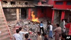 Youngsters look a church damaged and burned by angry Muslim mob in Jaranwala near Faisalabad, Pakistan, Aug. 16, 2023.