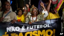 People hold a banner with a message that reads in Portuguese; "It isn't football, it is racism" during a protest against racism suffered by Brazilian soccer star Vinicius Junior who plays for Spain's Real Madrid, in Rio de Janeiro, Brazil, May 25, 2023.