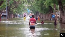 In this image made from video, residents move through floodwaters on a street in the town of Beledweyne, Somalia, Nov. 19, 2023. Officials say a cholera outbreak that started in Somalia in January is a consequence of the flooding in October and November.
