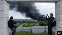 Foreign journalists report from an observation point while smoke rises after a Russian attack in Kharkiv, Ukraine, May 17, 2024.
