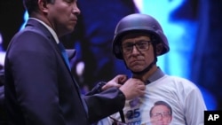 Wearing a bulletproof vest and ballistic helmet, presidential hopeful Christian Zurita, who was named to replace slain candidate Fernando Villavicencio, has his clothing adjusted during his closing campaign rally in Quito, Ecuador, Aug. 17, 2023.