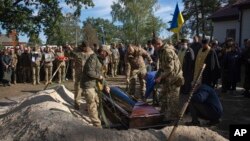 People attend a funeral ceremony for Lieutenant Colonel Vitali Baranov, commander of the 206th battalion of the Ukrainian army territorial defense, in Katiuzhanka near Kyiv, Ukraine, Oct. 11, 2023.
