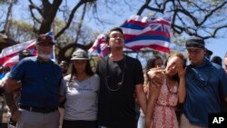 Community organizer Tiare Lawrence, second from right, is comforted by Archie Kalepa as they sing a song during a news conference with Lahaina, Hawaii, residents affected by the deadly wildfire in Lahaina, Aug. 18, 2023.