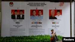 ILUSTRASI - Seorang pedagang kaki lima membawa barang dagangannya melewati spanduk bergambar paslon presiden dan wakil presiden untuk Pemilu mendatang di Jakarta, 12 Januari 2024. (REUTERS/Willy Kurniawan)