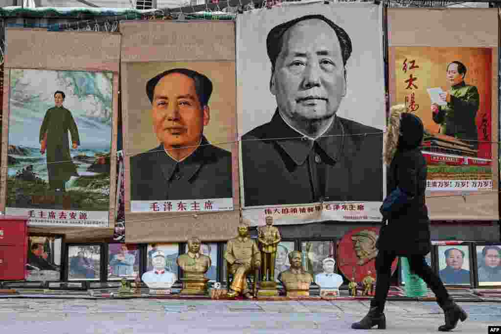 Seorang perempuan berjalan melewati gambar mendiang pemimpin Komunis China Mao Zedong di sebuah kios di pasar barang antik di Beijing, pada peringatan 130 tahun pendiri negara komunis China.