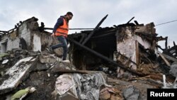 A volunteer inspects the ruins of a residential building hit by a Russian missile strike in Zaporizhzhia, Ukraine, April 9, 2023. 